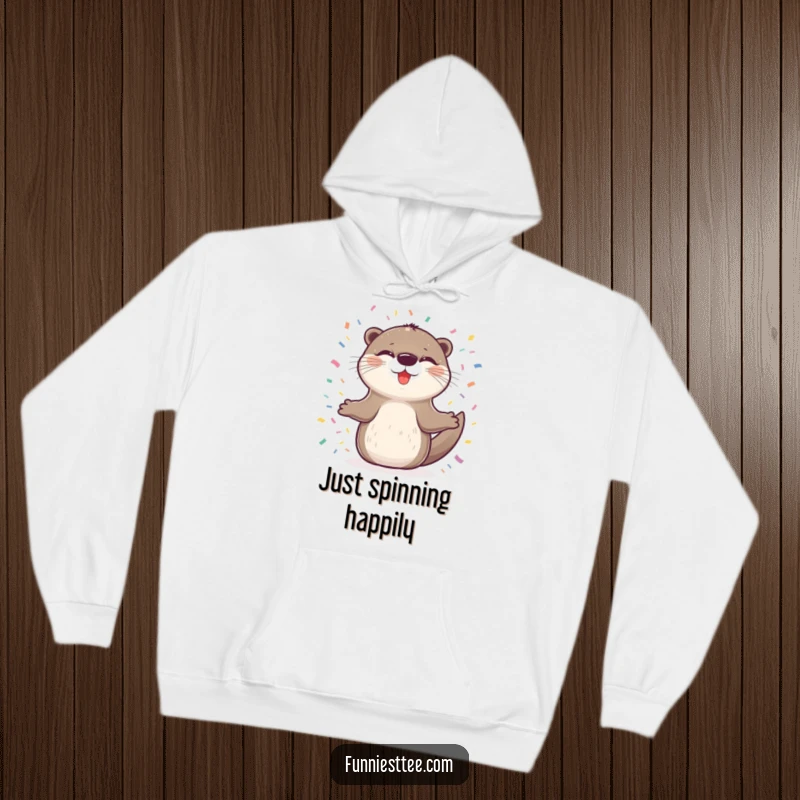 Funny hoodie featuring a delighted otter with closed eyes, spinning happily in a circle of confetti, perfect for cozy moments of pure joy.